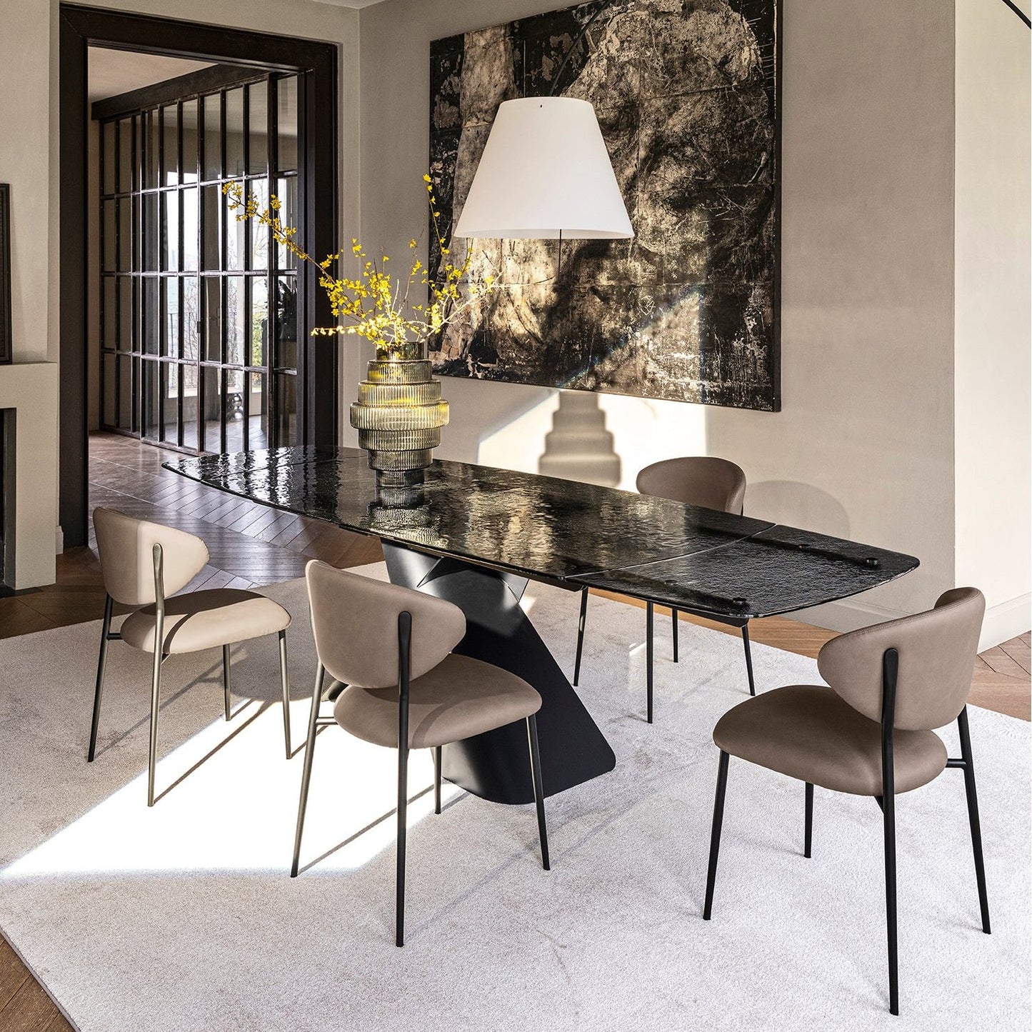 Modern dining room with a grey glass table and beige chairs.