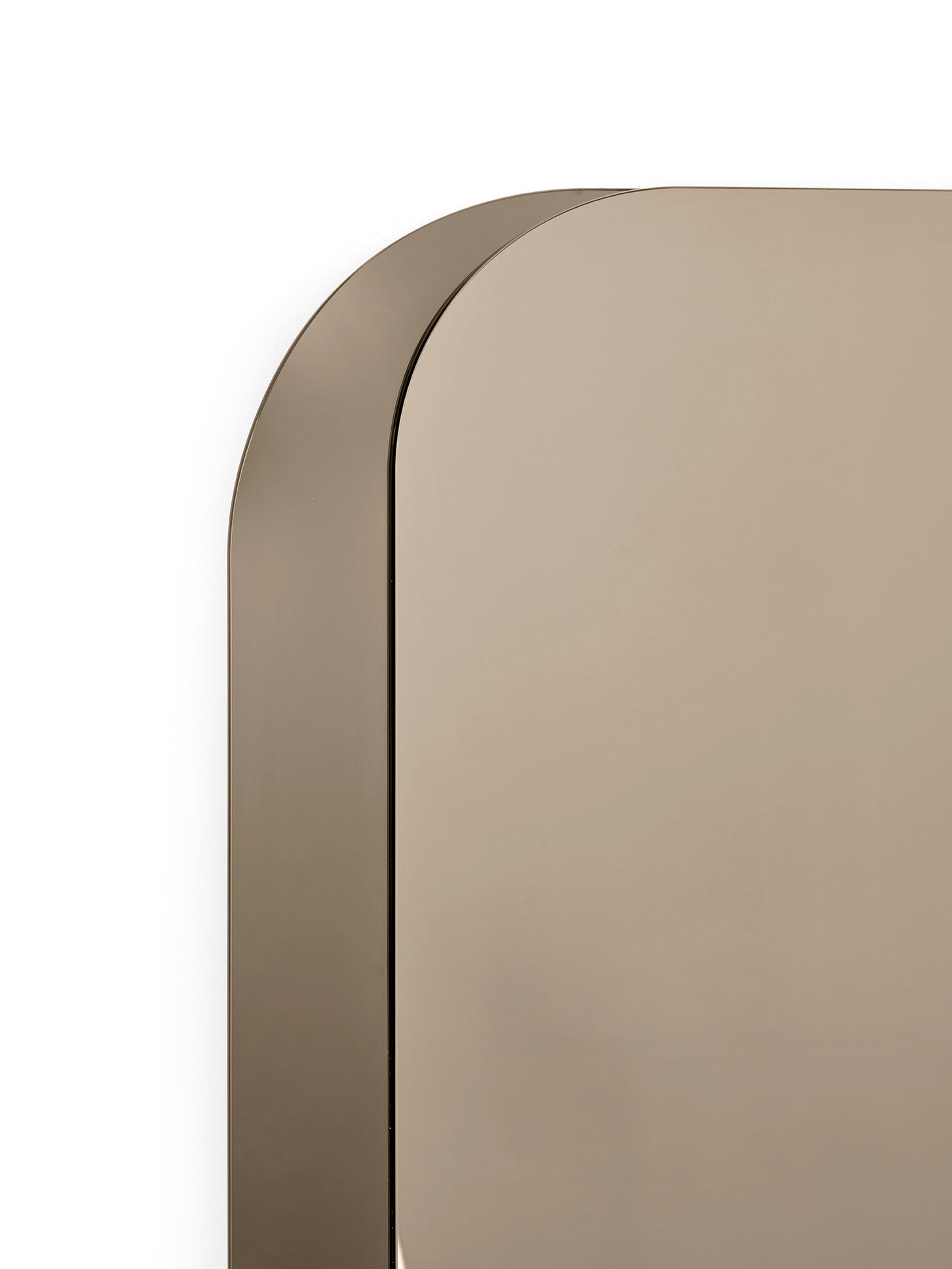 Close-up of a minimalist wall mirror with a rounded top-left corner and a warm taupe-beige reflective surface, set against a solid white background.