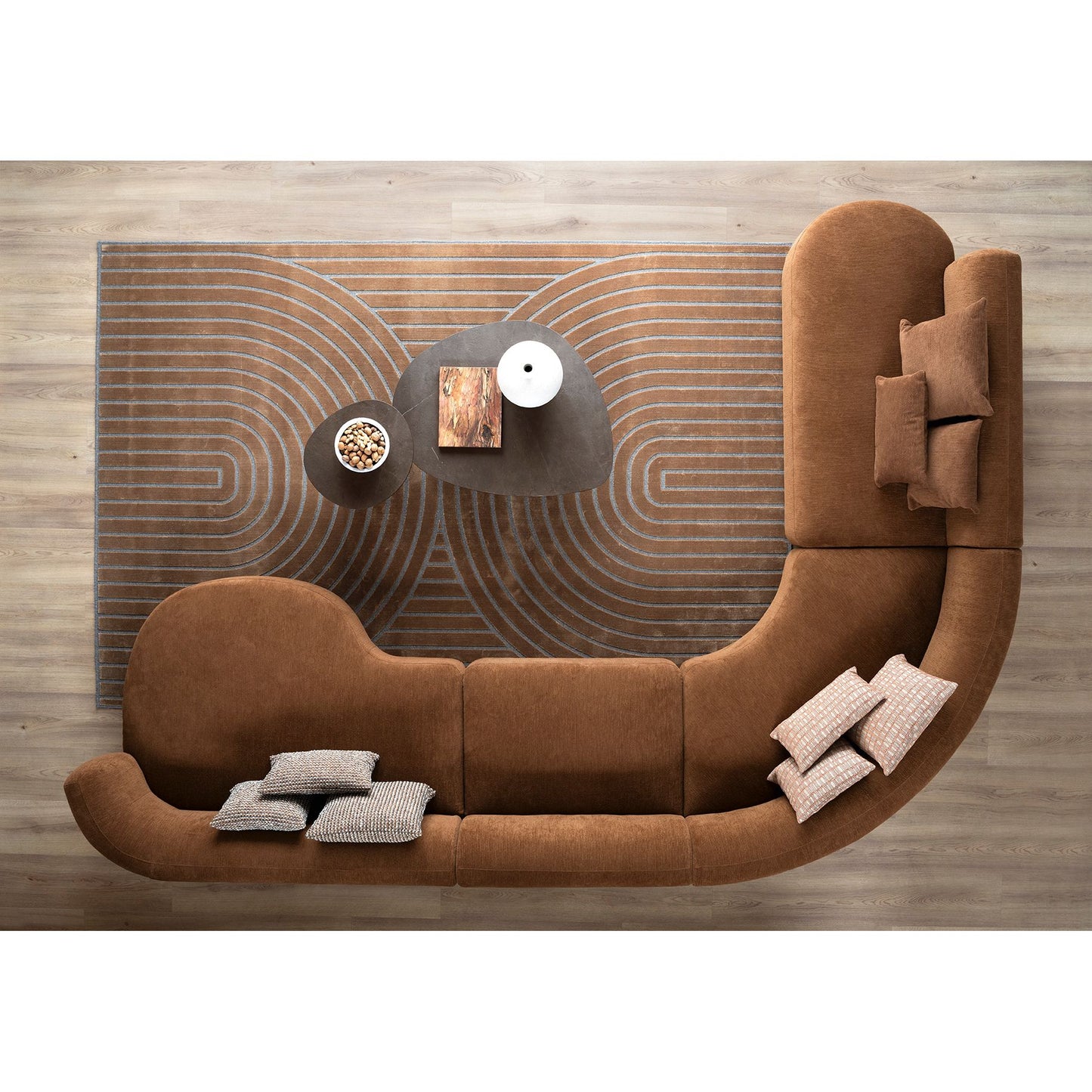 Brown sectional sofa with decorative pillows and a coffee table against a wooden wall.
